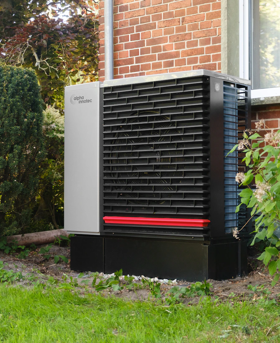 Warmtepomp naast de bakstenen gevel van een woning